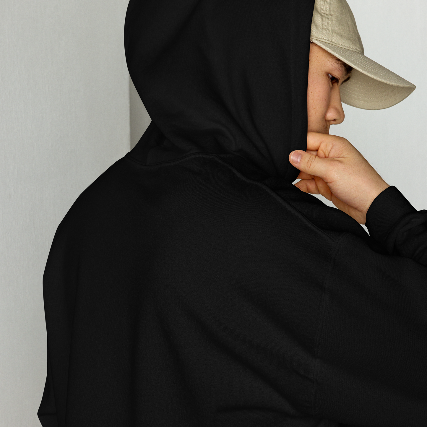 Person in a baseball hat wearing a black hoodie with a neutral background for Creepy All Year
