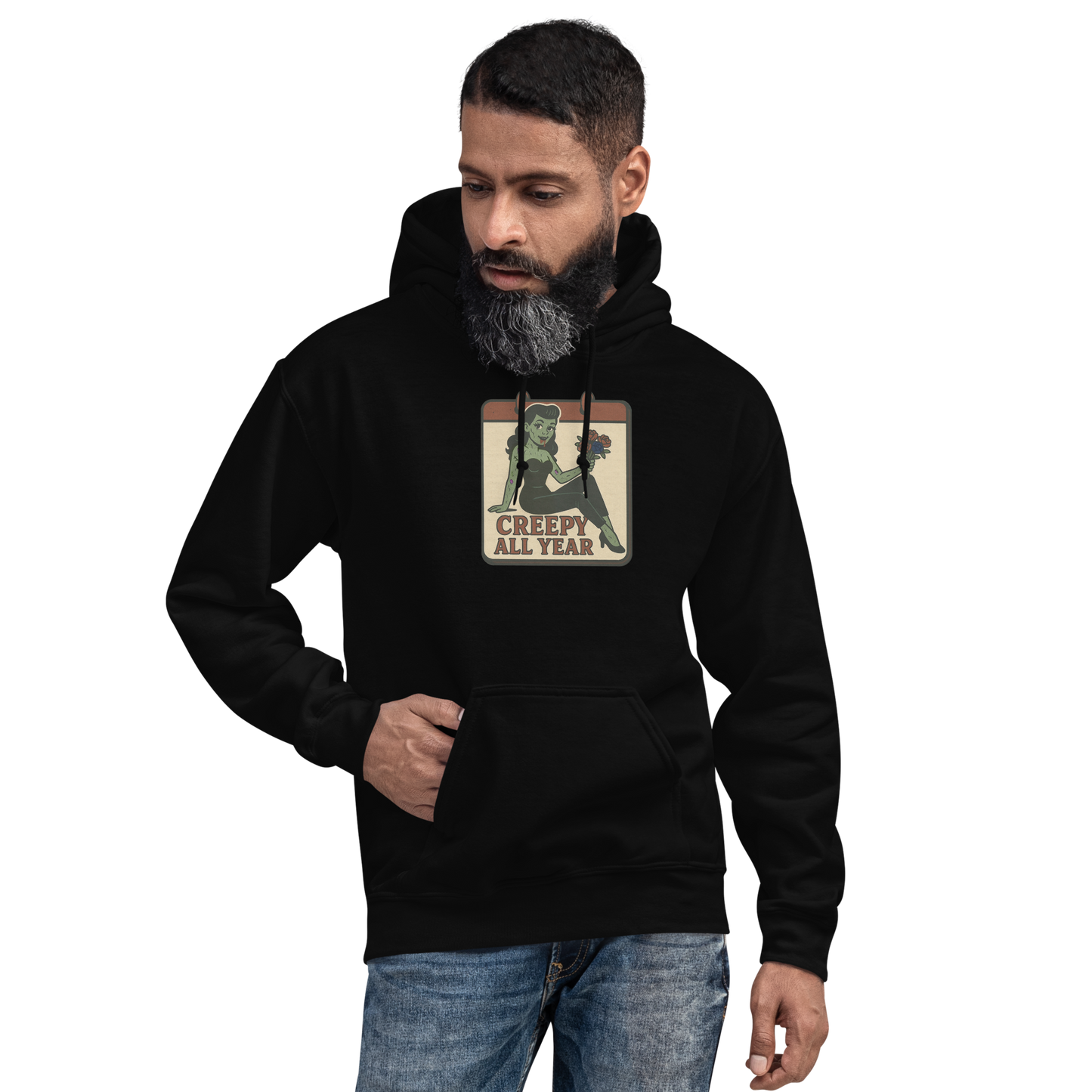 A black hoodie on a man with black hair and beard with a vintage-style design on the front. The design features a green pinup-style zombie girl holding flowers, with a banner underneath that reads “CREEPY ALL YEAR.”
