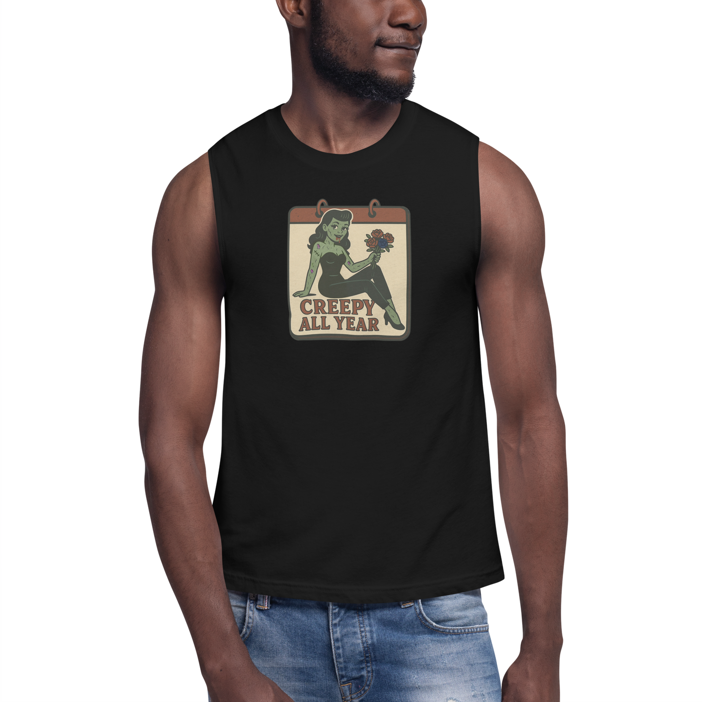 A man wearing jeans and muscle shirt with vintage style design. The design on the front features a green pinup-style zombie girl holding flowers, with a banner underneath that reads “CREEPY ALL YEAR.”