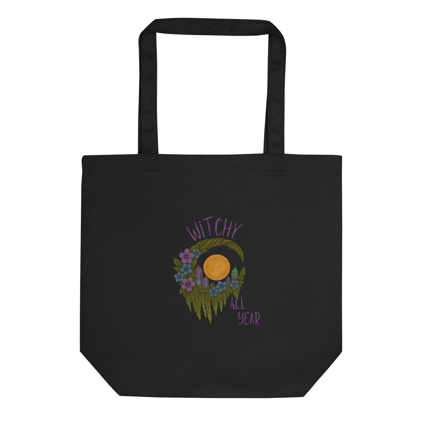 This is a black eco tote bag with a design of a hand-drawn wreath made of moss-covered branches wraps around a glowing sun. The wreath is decorated with purple and blue flowers, small amethyst and fluorite crystals, and strands of hanging moss. The words “Witchy” curve above the wreath and “All Year” sits on the bottom right