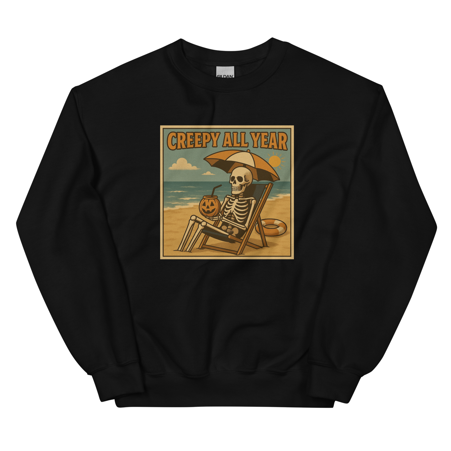 This is a black sweatshirt with a retro-style illustration of a grinning skeleton lounging on a beach chair under an orange umbrella. The skeleton is holding a pumpkin-shaped drink cup with a straw and relaxing by the ocean, with a bright sun in the sky and a life preserver in the sand. The words “Creepy All Year” appear boldly at the top