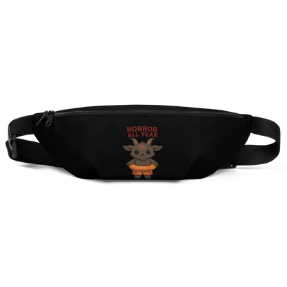 This is a black waist bag fanny pack that has a cartoon illustration of a baby Baphomet goat with curved horns and a playful grin, wearing bright floral swim trunks while floating in a colorful inner tube. The character is set against a light background with the bold text “Horror All Year” above in red letters 