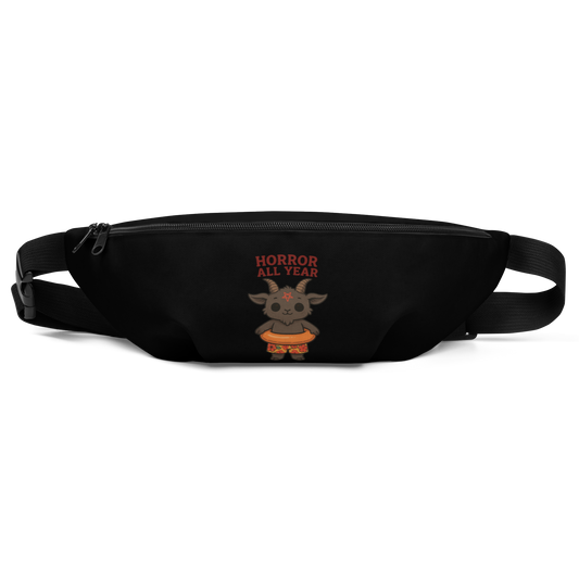 This is a black waist bag fanny pack that has a cartoon illustration of a baby Baphomet goat with curved horns and a playful grin, wearing bright floral swim trunks while floating in a colorful inner tube. The character is set against a light background with the bold text “Horror All Year” above in red letters 