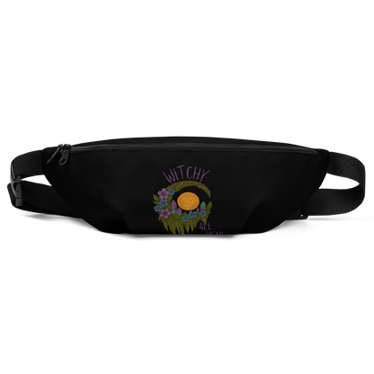 This is a black waist bag fanny pack with a design of a hand-drawn wreath made of moss-covered branches wraps around a glowing sun. The wreath is decorated with purple and blue flowers, small amethyst and fluorite crystals, and strands of hanging moss. The words “Witchy” curve above the wreath and “All Year” sits on the bottom right 