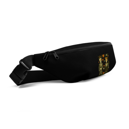 This is a black waist bag showing the clasp with a Día de los Muertos–style illustration of a male and female skeleton holding hands, surrounded by marigolds, vines, and folk art patterns. The skeletons wear traditional black clothing, the man in a suit and hat, the woman with a floral crown with a red heart and leaves at the bottom and the text Creepy All Year. Rendered in warm tones of orange, green, and cream, symbolizing eternal love and remembrance