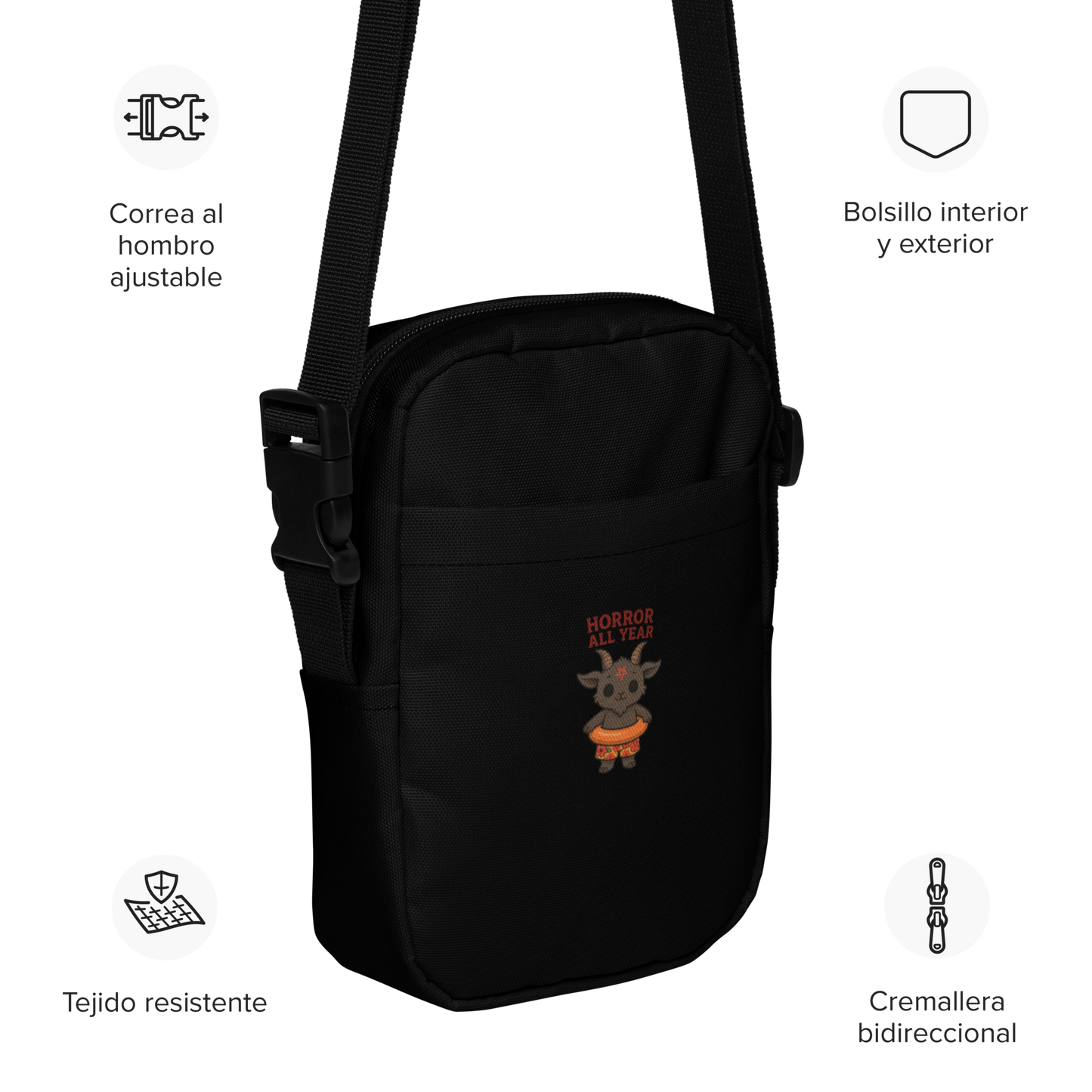 This is a black crossbody bag with a cartoon illustration of a baby Baphomet goat with curved horns and a playful grin, wearing bright floral swim trunks while floating in a colorful inner tube. The character is set against a light background with the bold text “Horror All Year” above in red letters