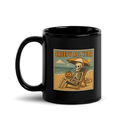 This is a black glossy mug with a retro-style illustration of a grinning skeleton lounging on a beach chair under an orange umbrella. The skeleton is holding a pumpkin-shaped drink cup with a straw and relaxing by the ocean, with a bright sun in the sky and a life preserver in the sand. The words “Creepy All Year” appear boldly at the top on the front side