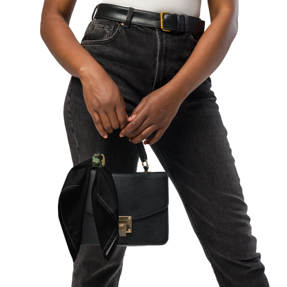 Person holding a black handbag with a balck scarf on it. The design features a green pinup-style zombie girl holding flowers, with a banner underneath that reads “CREEPY ALL YEAR.”