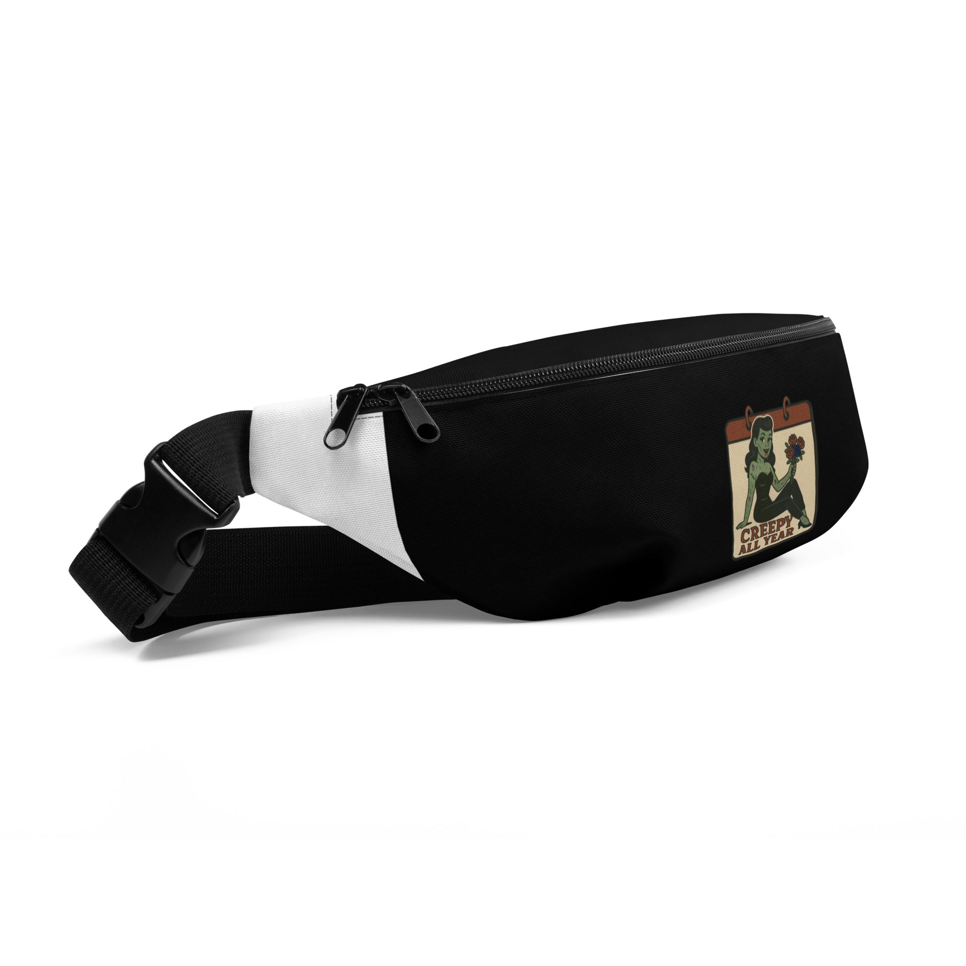 Black side of a shoulder or fanny pack with a graphic design. The design features a green pinup-style zombie girl holding flowers, with a banner underneath that reads “CREEPY ALL YEAR.”