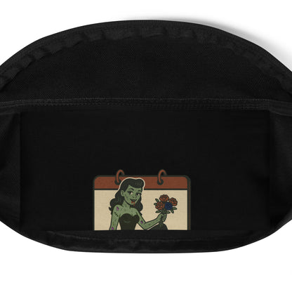 Black shoulder pack with a graphic design zoomed in. The design features a green pinup-style zombie girl holding flowers, with a banner underneath that reads “CREEPY ALL YEAR.”