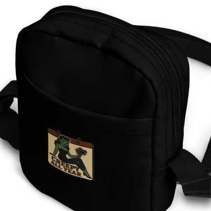 Black crossbody bag with a patch featuring a green pinup zombie with the text Creepy All Year
