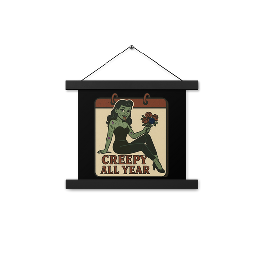 Black hanging wall art with two wood pieces on the top and bottom and a black hanger with a vintage-style patch on the design. The design features a green pinup-style zombie girl holding flowers, with a banner underneath that reads “CREEPY ALL YEAR.”