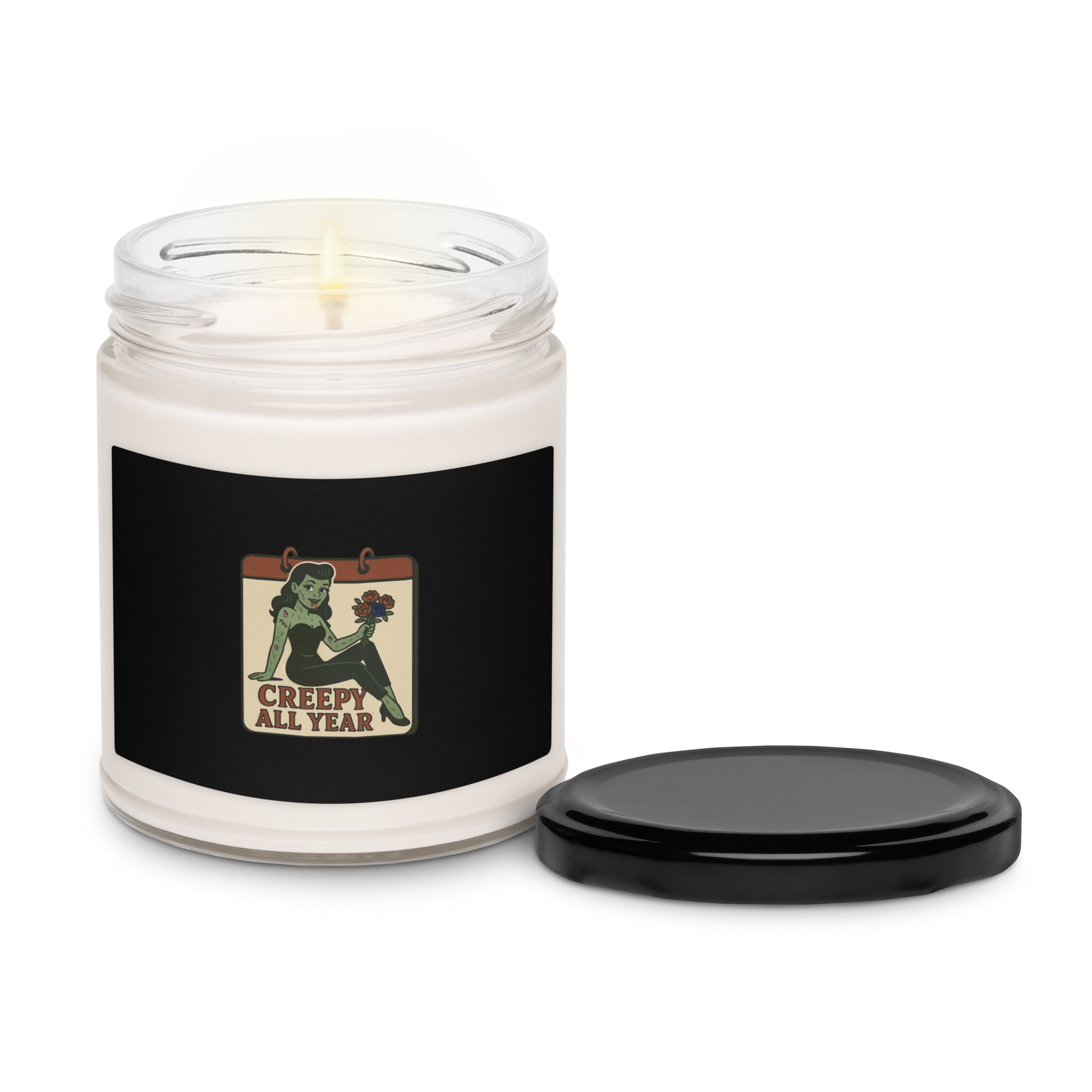White candle in a jar with a black label featuring a zombie graphic and text that reads Creepy All Year