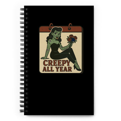 Spiral black notebook. The design features a green pinup-style zombie girl holding flowers, with a banner underneath that reads “CREEPY ALL YEAR.”