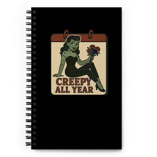 Spiral black notebook. The design features a green pinup-style zombie girl holding flowers, with a banner underneath that reads “CREEPY ALL YEAR.”