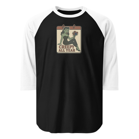 A black and white raglan t-shirt with a small vintage-style design. The design features a green pinup-style zombie girl holding flowers, with a banner underneath that reads “CREEPY ALL YEAR.”