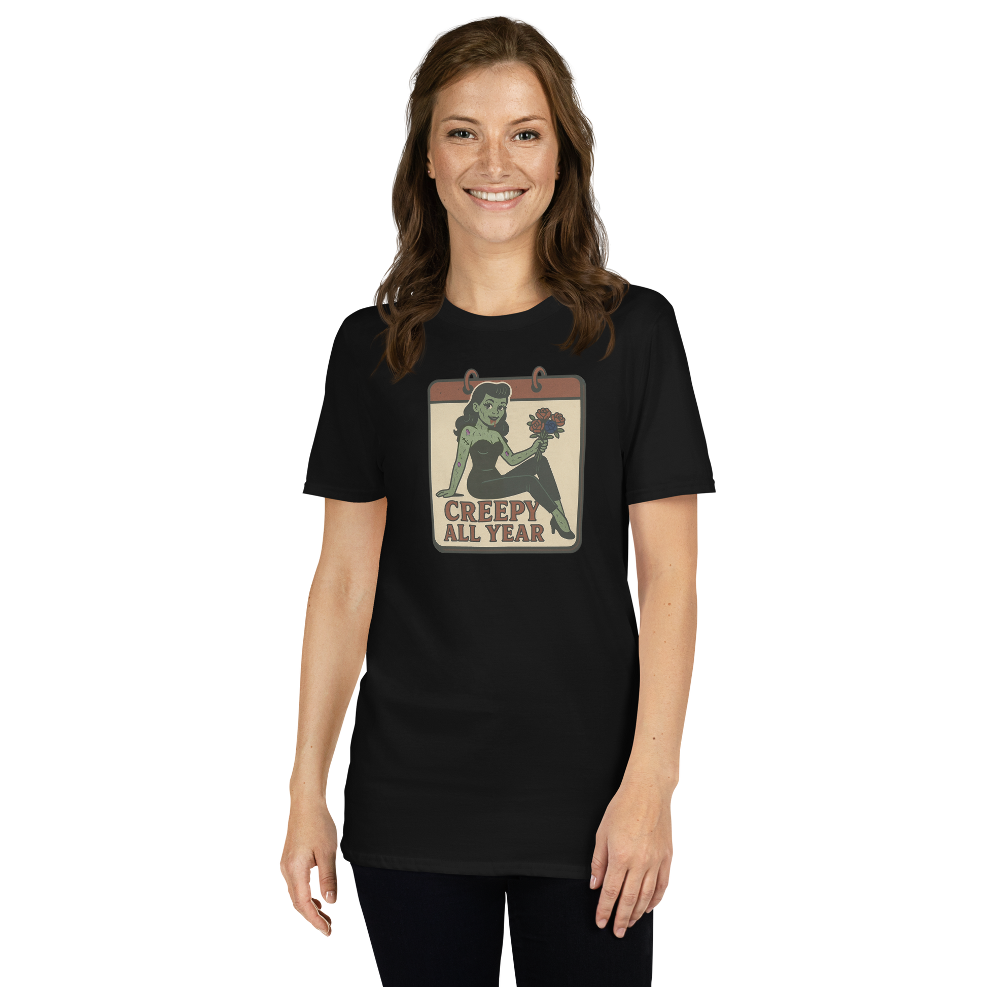 A t-shirt on a girl with brown hair with a vintage-style design on the front. The design features a green pinup-style zombie girl holding flowers, with a banner underneath that reads “CREEPY ALL YEAR.”