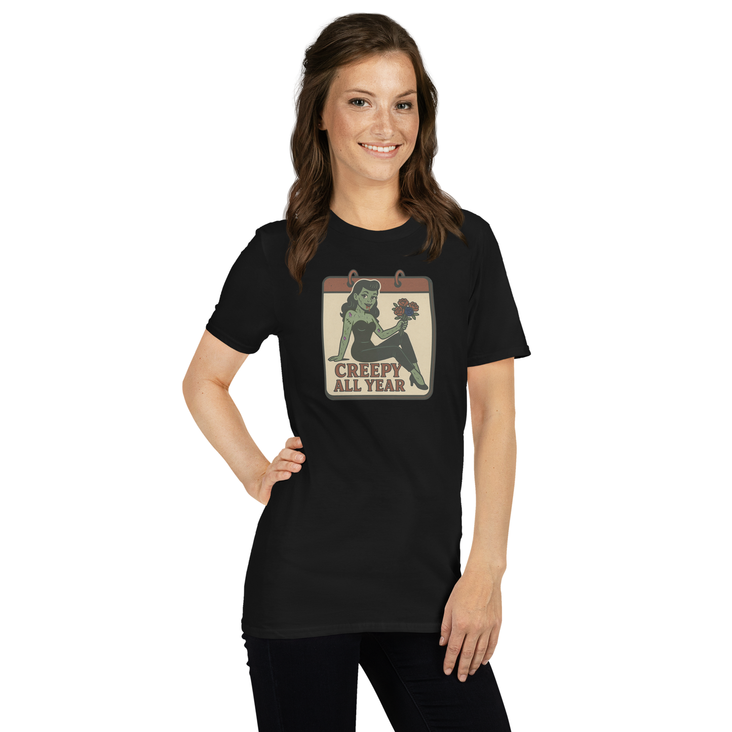 A girl with long brown hair wearing black pants and t-shirt with vintage style design. The design on the front features a green pinup-style zombie girl holding flowers, with a banner underneath that reads “CREEPY ALL YEAR.”