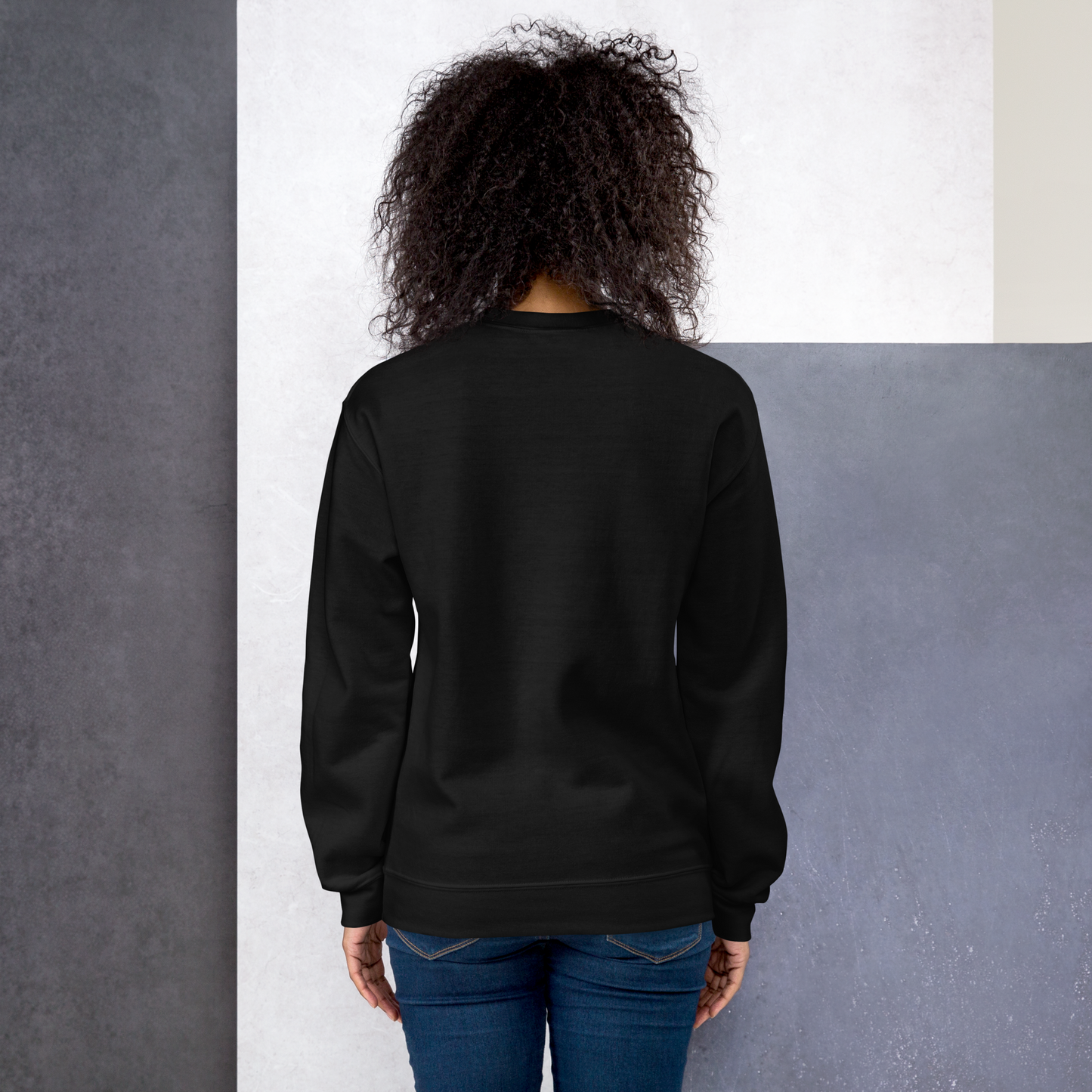 A back of a black sweatshirt on a girl with black hair with a vintage-style design on the front. “CREEPY ALL YEAR.”