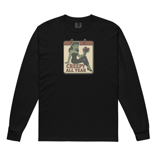 A black long sleeve t-shirt. The design features a green pinup-style zombie girl holding flowers, with a banner underneath that reads “CREEPY ALL YEAR.”