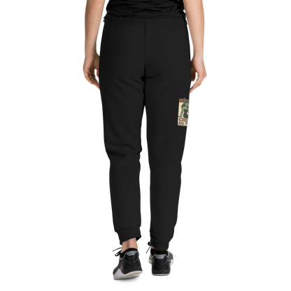 Back of black joggers on a girl with a black t-shirt, with a vintage-style design on the front. The design features a green pinup-style zombie girl holding flowers, with a banner underneath that reads “CREEPY ALL YEAR.”