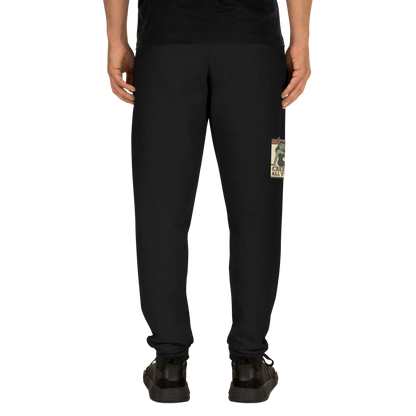 Back of black lack joggers on a man with a black t-shirt, with a vintage-style design on the front. The design features a green pinup-style zombie girl holding flowers, with a banner underneath that reads “CREEPY ALL YEAR.”
