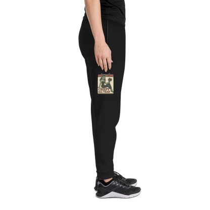Black joggers on a person with a black t-shirt and grey tennis shoes, with a vintage-style design on the front. The design features a green pinup-style zombie girl holding flowers, with a banner underneath that reads “CREEPY ALL YEAR.”