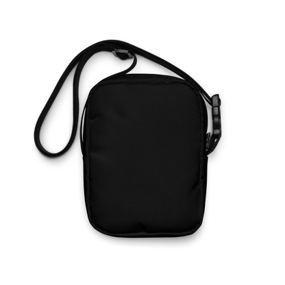 This is the back of a black crossbody bag that has a bored skeleton with his head resting in his hand and he has spider webs and bats around him and the text reads just waiting for October on the front