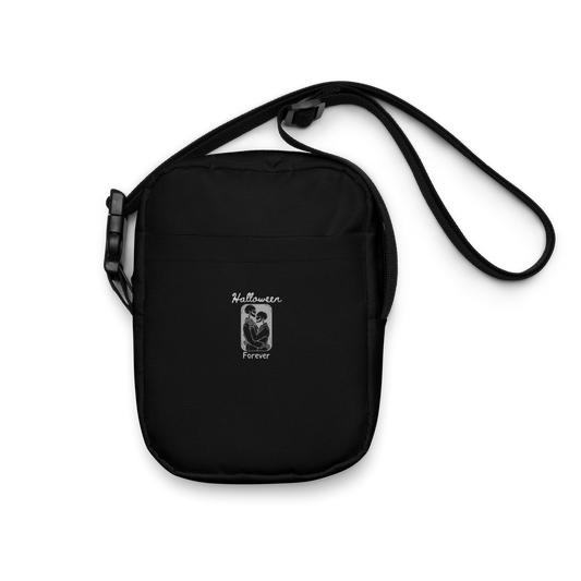 This is a black crossbody bag that has a hugging skeleton couple that is grey and says Halloween Forever 