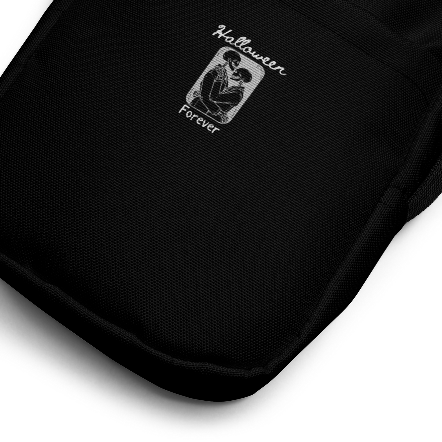 This is a close up of a black crossbody bag that has a hugging skeleton couple that is grey and says Halloween Forever 