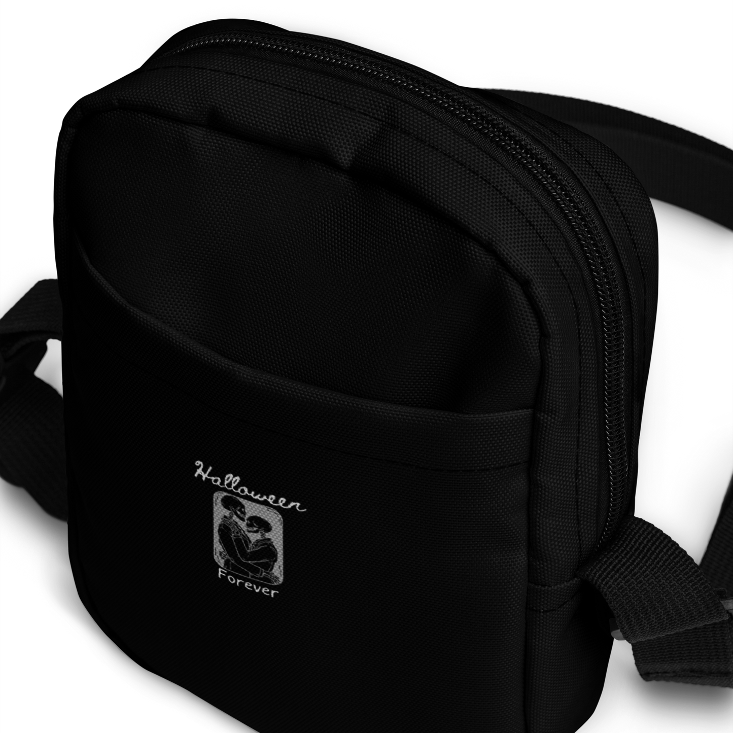 This is a black crossbody bag that has a hugging skeleton couple that is grey and says Halloween Forever 