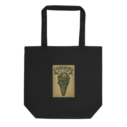 This is a black tote bag that is a vintage-style illustration of a zombie-themed ice cream cone with a green, melting undead face and bulging eyeballs. Above the cone, a horror banner reads "Horror All Year" on a distressed parchment background