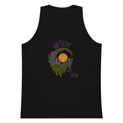This is a black mens tank top with a design of a hand-drawn wreath made of moss-covered branches wraps around a glowing sun. The wreath is decorated with purple and blue flowers, small amethyst and fluorite crystals, and strands of hanging moss. The words “Witchy” curve above the wreath and “All Year” sits on the bottom right 
