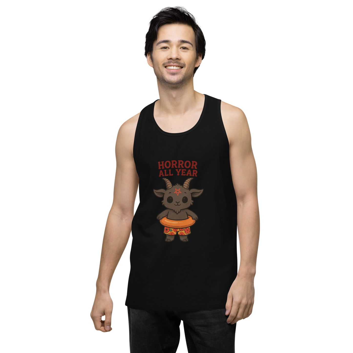 This is a man with dark hair wearing a black tank top with a cartoon illustration of a baby Baphomet goat with curved horns and a playful grin, wearing bright floral swim trunks while floating in a colorful inner tube. The character is set against a light background with the bold text “Horror All Year” above in red letters