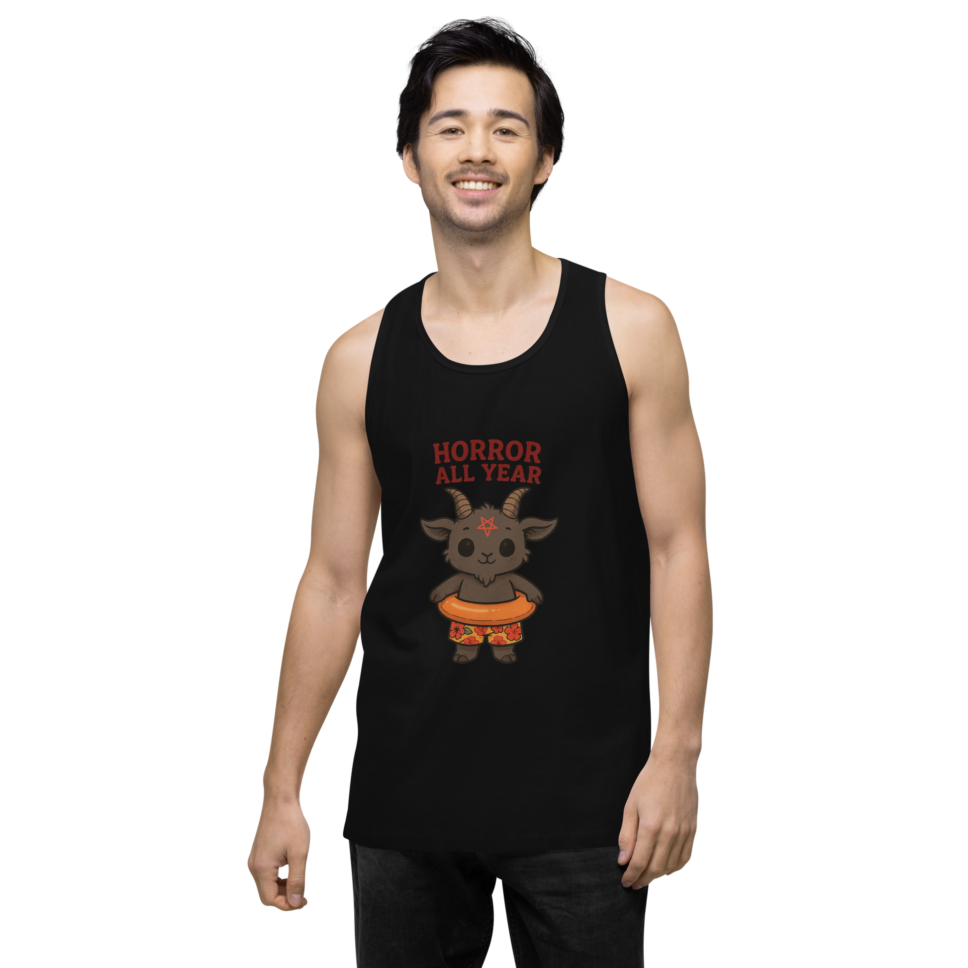 This is a man with dark hair wearing a black tank top with a cartoon illustration of a baby Baphomet goat with curved horns and a playful grin, wearing bright floral swim trunks while floating in a colorful inner tube. The character is set against a light background with the bold text “Horror All Year” above in red letters