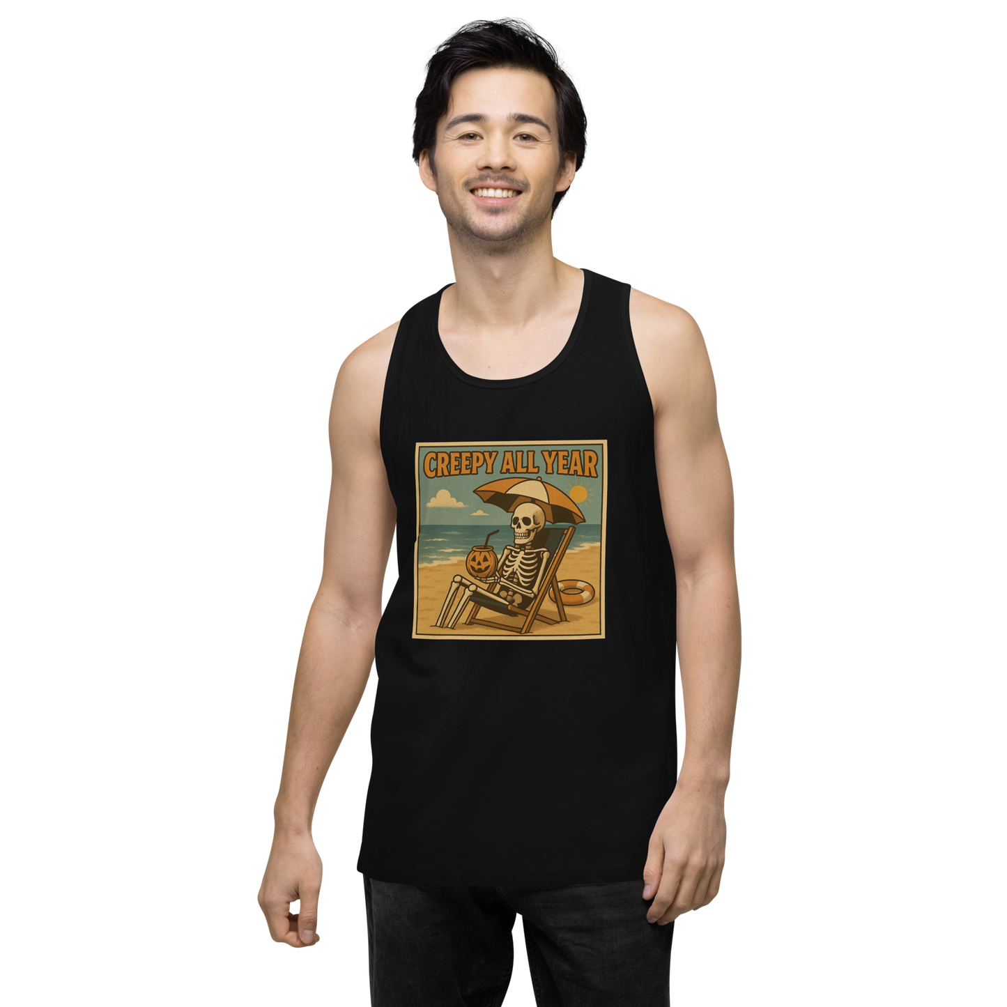 This is a man with dark hair wearing a black tank top with a retro-style illustration of a grinning skeleton lounging on a beach chair under an orange umbrella. The skeleton is holding a pumpkin-shaped drink cup with a straw and relaxing by the ocean, with a bright sun in the sky and a life preserver in the sand. The words “Creepy All Year” appear boldly at the top 