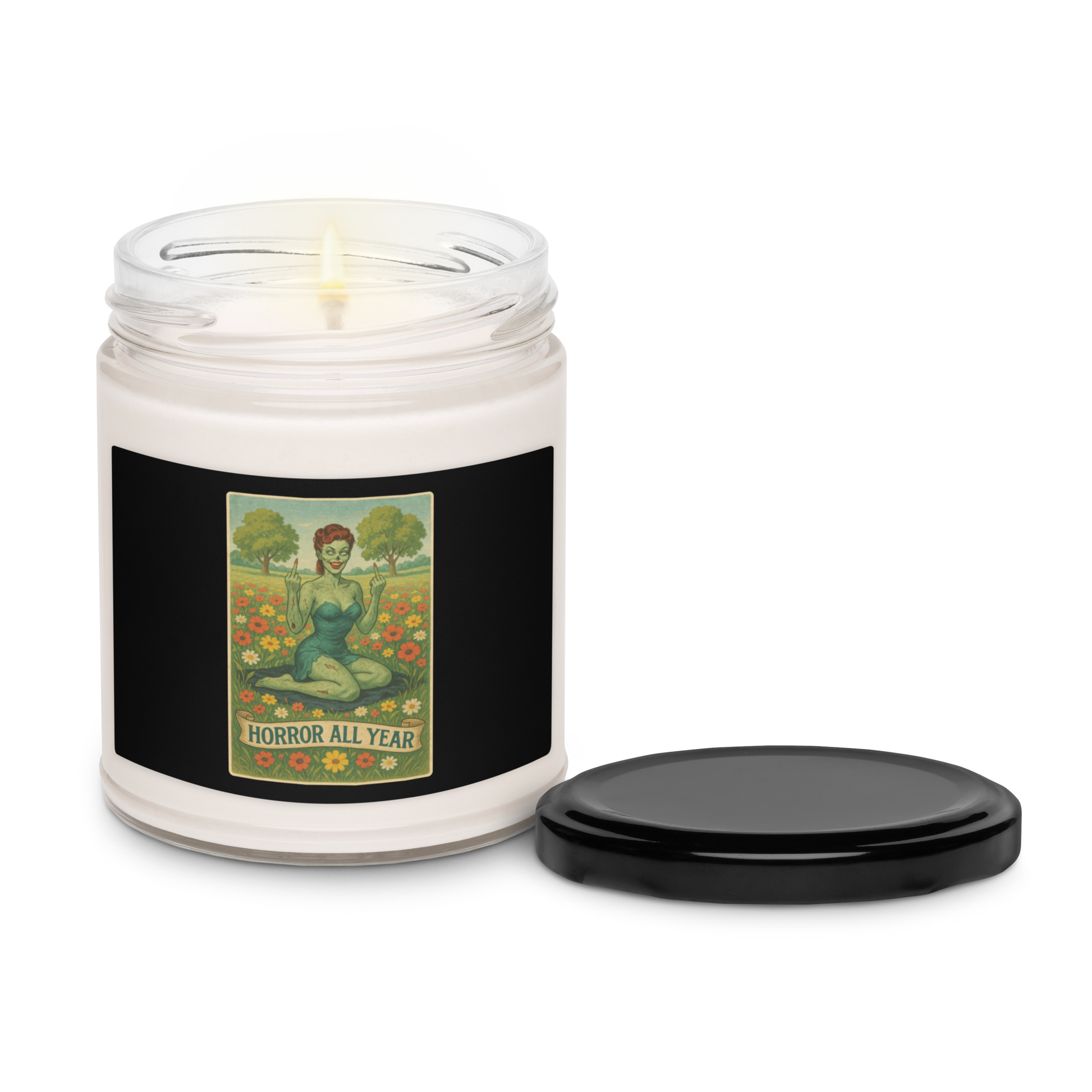 This is a candle with a black tin lid and a black label with a design illustration of a sassy zombie pinup girl standing in a floral field, wearing tattered lingerie and flipping off the viewer with both hands. She has green skin, vintage curls, and a bold attitude. The design blends horror and humor, with a pastel color palette and creepy cute vibes