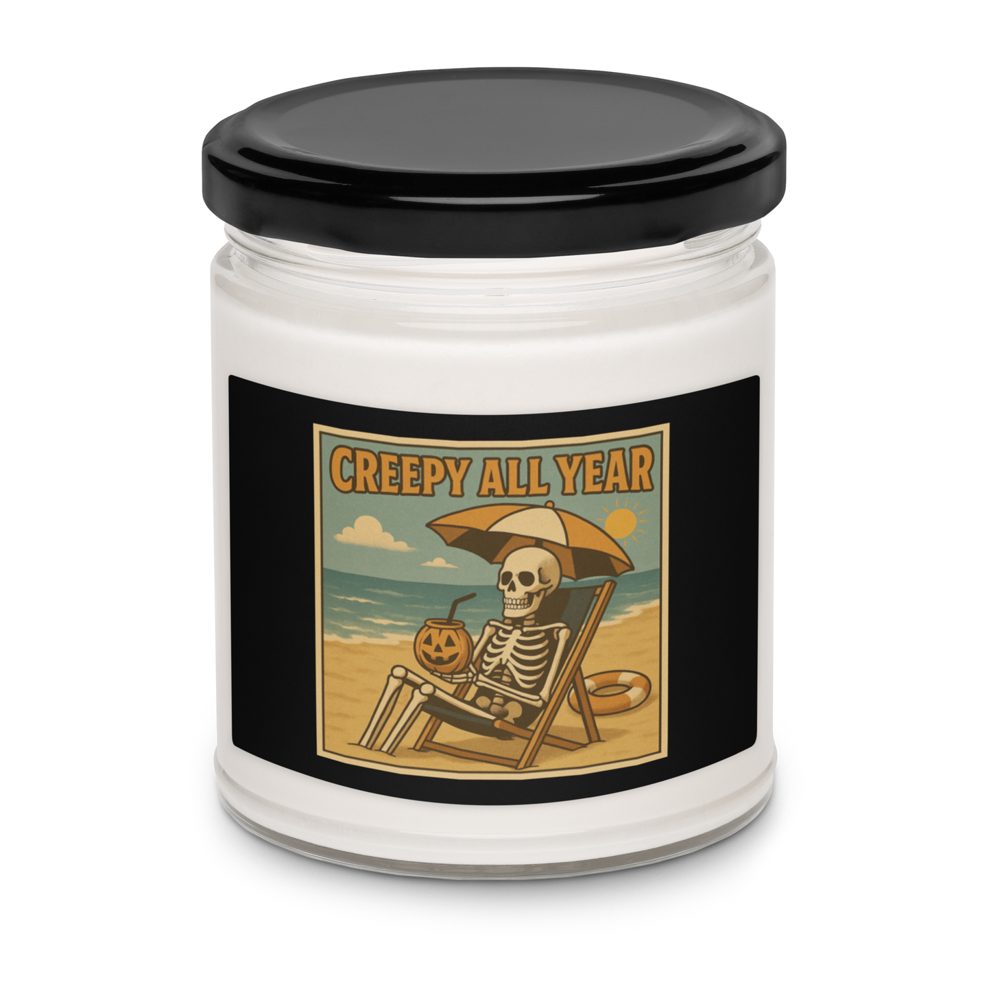 This is a white candle with black tin lid and black label with a retro-style illustration of a grinning skeleton lounging on a beach chair under an orange umbrella. The skeleton is holding a pumpkin-shaped drink cup with a straw and relaxing by the ocean, with a bright sun in the sky and a life preserver in the sand. The words “Creepy All Year” appear boldly at the top 