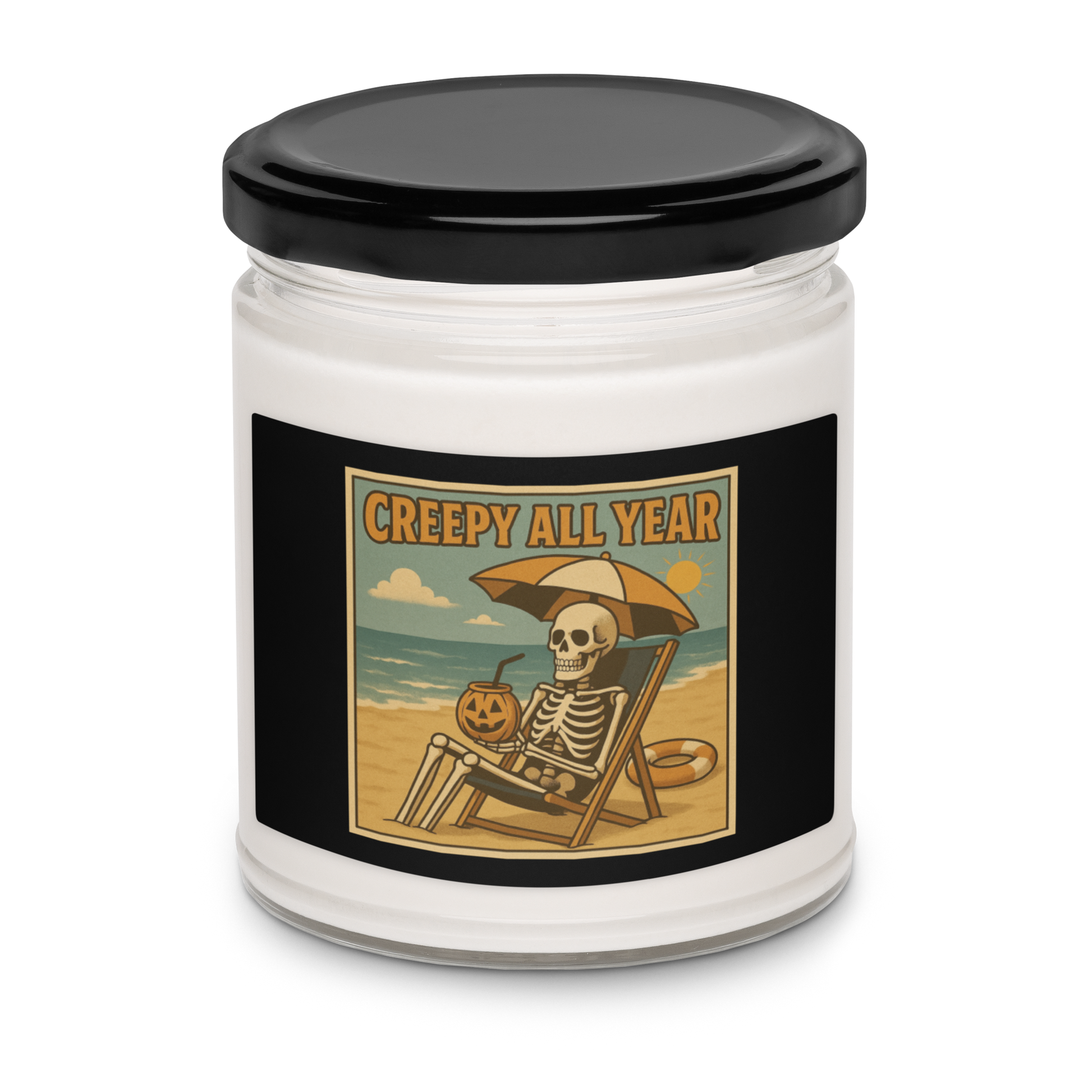 This is a white candle with black tin lid and black label with a retro-style illustration of a grinning skeleton lounging on a beach chair under an orange umbrella. The skeleton is holding a pumpkin-shaped drink cup with a straw and relaxing by the ocean, with a bright sun in the sky and a life preserver in the sand. The words “Creepy All Year” appear boldly at the top 