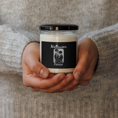 This is a woman holding a candle with a black label that has a hugging skeleton couple that is grey and says Halloween Forever 
