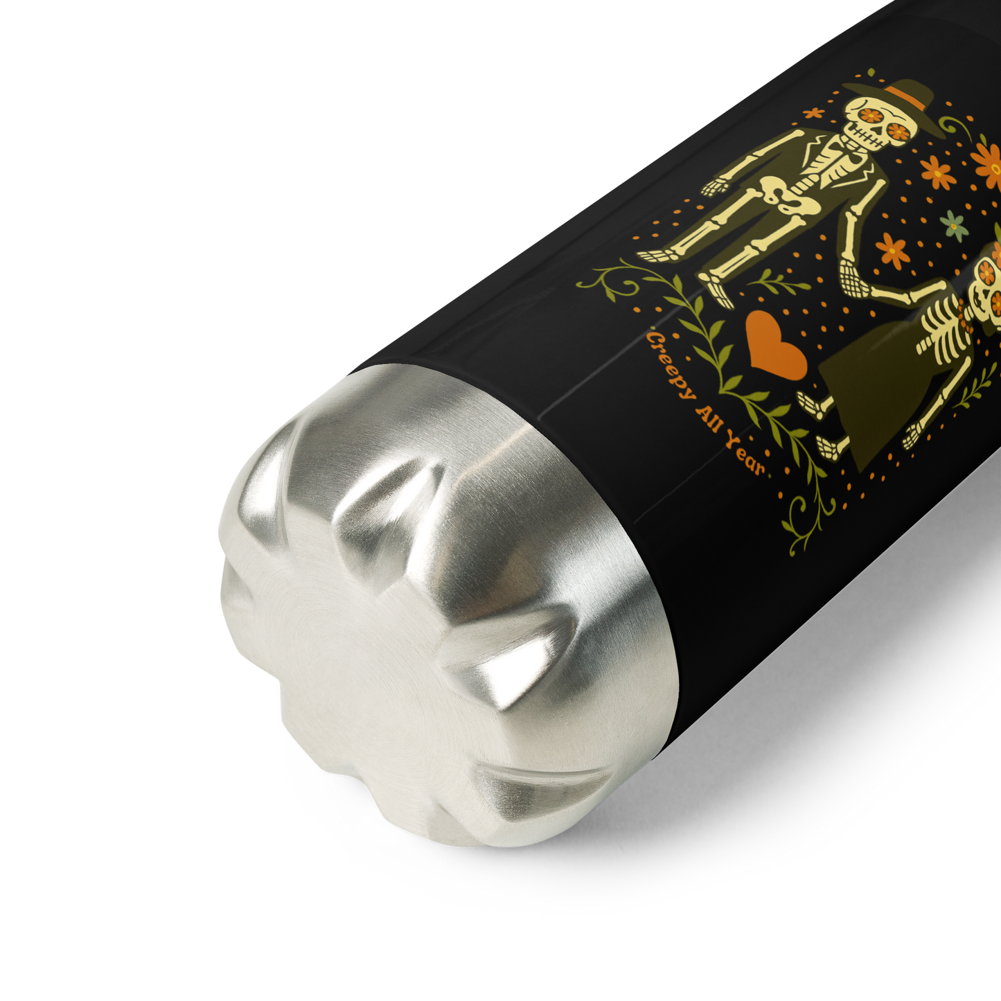 This is a zoom in of a black and stainless steel water bottle with a Día de los Muertos–style illustration of a male and female skeleton holding hands, surrounded by marigolds, vines, and folk art patterns. The skeletons wear traditional black clothing, the man in a suit and hat, the woman with a floral crown with a red heart and leaves at the bottom and the text Creepy All Year. Rendered in warm tones of orange, green, and cream, symbolizing eternal love and remembrance