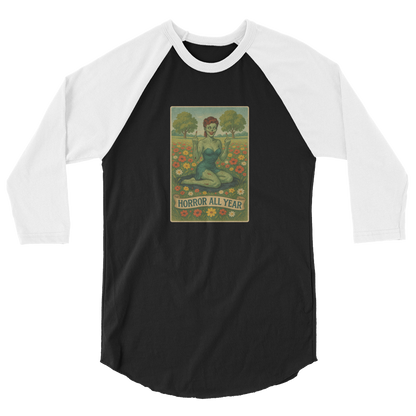 This is a black and white raglan shirt with a design illustration of a sassy zombie pinup girl standing in a floral field, wearing tattered lingerie and flipping off the viewer with both hands. She has green skin, vintage curls, and a bold attitude. The design blends horror and humor, with a pastel color palette and creepy cute vibes
