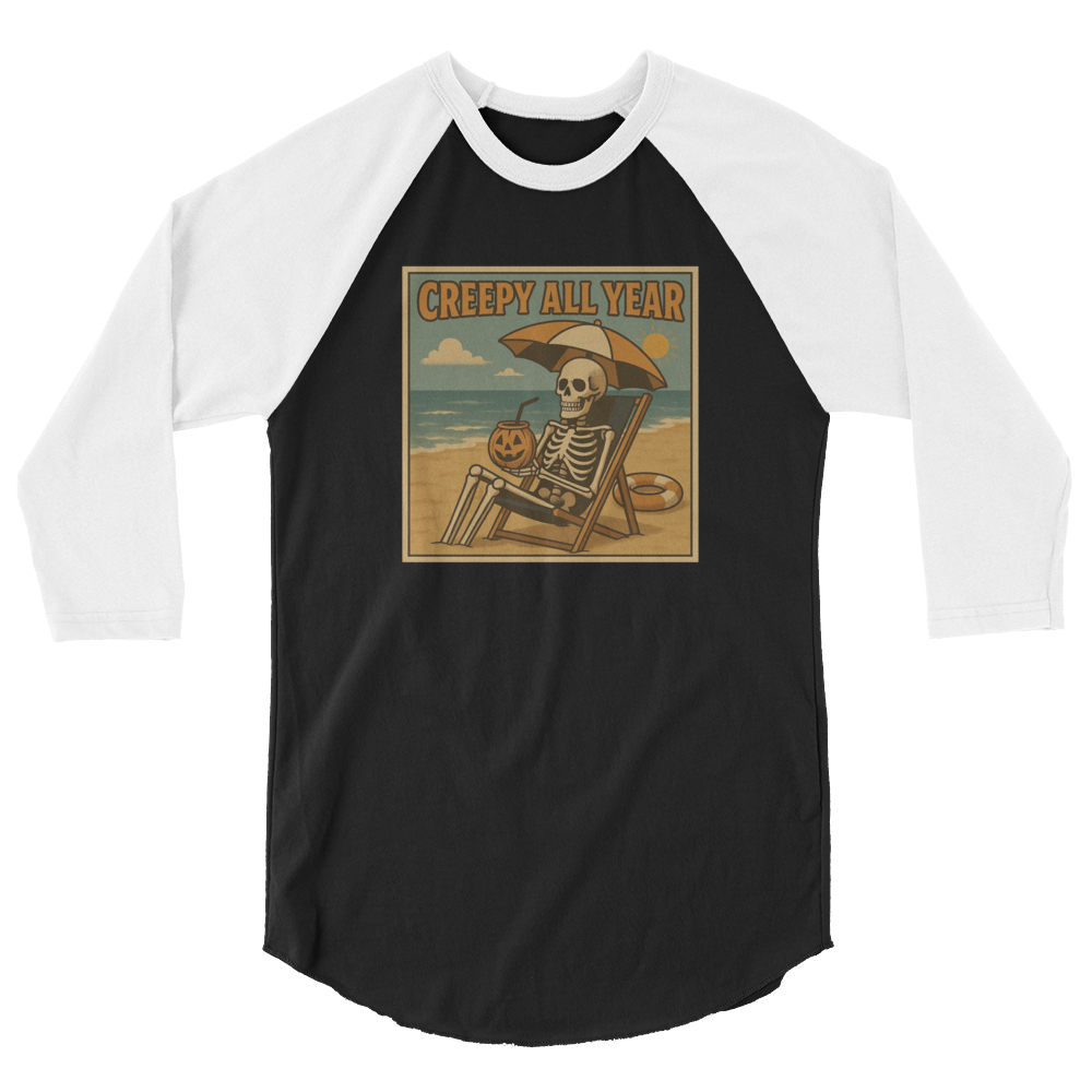 This is a black and white raglan shirt with a retro-style illustration of a grinning skeleton lounging on a beach chair under an orange umbrella. The skeleton is holding a pumpkin-shaped drink cup with a straw and relaxing by the ocean, with a bright sun in the sky and a life preserver in the sand. The words “Creepy All Year” appear boldly at the top