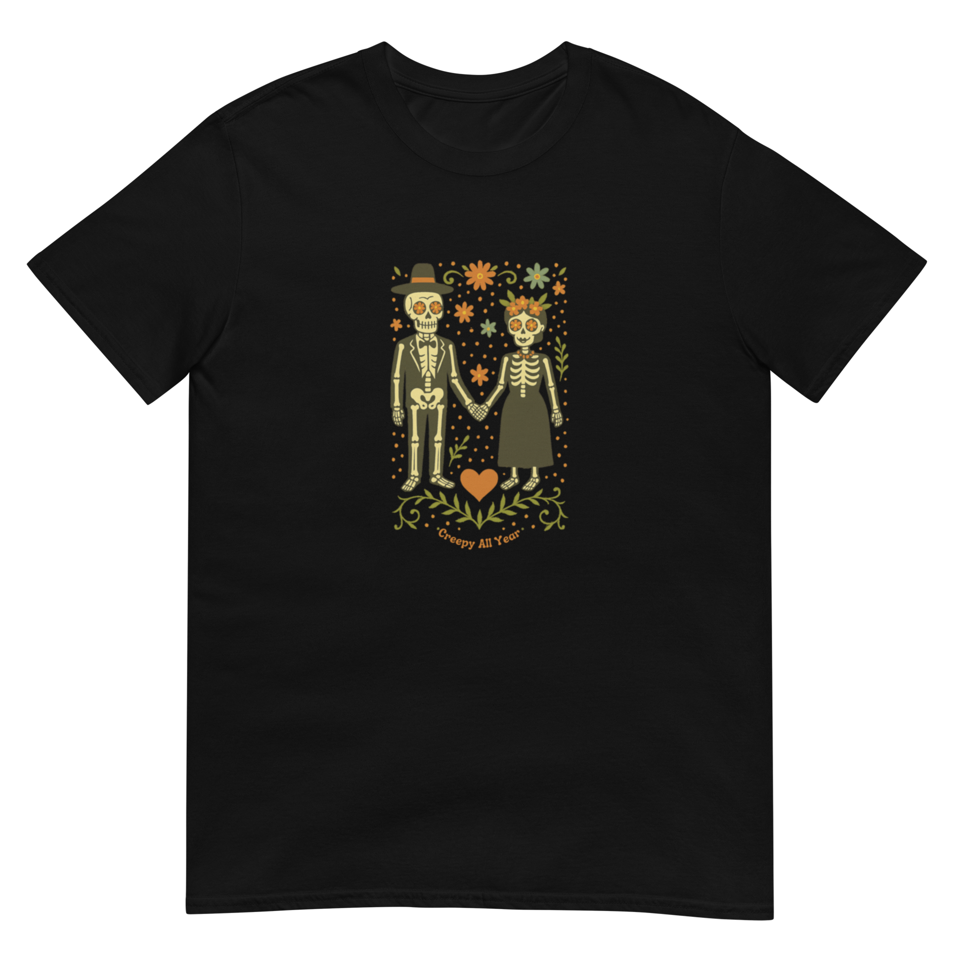 This is a black t-shirt with a Día de los Muertos–style illustration of a male and female skeleton holding hands, surrounded by marigolds, vines, and folk art patterns. The skeletons wear traditional black clothing, the man in a suit and hat, the woman with a floral crown with a red heart and leaves at the bottom and the text Creepy All Year. Rendered in warm tones of orange, green, and cream, symbolizing eternal love and remembrance