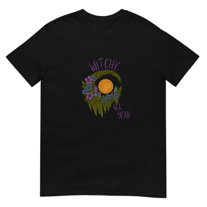 This is a black t-shirt with a design of a hand-drawn wreath made of moss-covered branches wraps around a glowing sun. The wreath is decorated with purple and blue flowers, small amethyst and fluorite crystals, and strands of hanging moss. The words “Witchy” curve above the wreath and “All Year” sits on the bottom right 