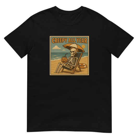 This is a black t-shirt with a retro-style illustration of a grinning skeleton lounging on a beach chair under an orange umbrella. The skeleton is holding a pumpkin-shaped drink cup with a straw and relaxing by the ocean, with a bright sun in the sky and a life preserver in the sand. The words “Creepy All Year” appear boldly at the top