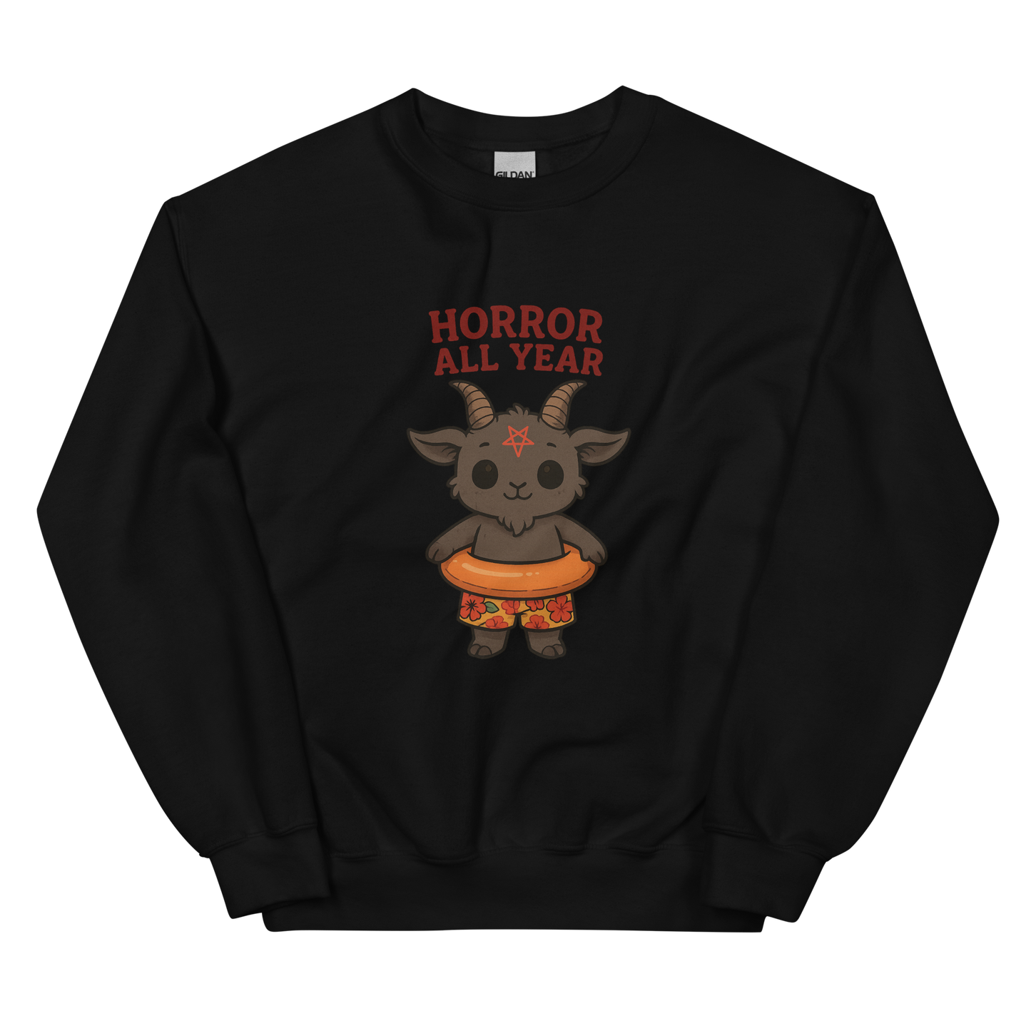 This is a black sweatshirt with a cartoon illustration of a baby Baphomet goat with curved horns and a playful grin, wearing bright floral swim trunks while floating in a colorful inner tube. The character is set against a light background with the bold text “Horror All Year” above in red letters
