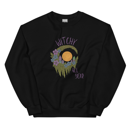 This is a black sweatshirt with a design of a hand-drawn wreath made of moss-covered branches wraps around a glowing sun. The wreath is decorated with purple and blue flowers, small amethyst and fluorite crystals, and strands of hanging moss. The words “Witchy” curve above the wreath and “All Year” sits on the bottom right 