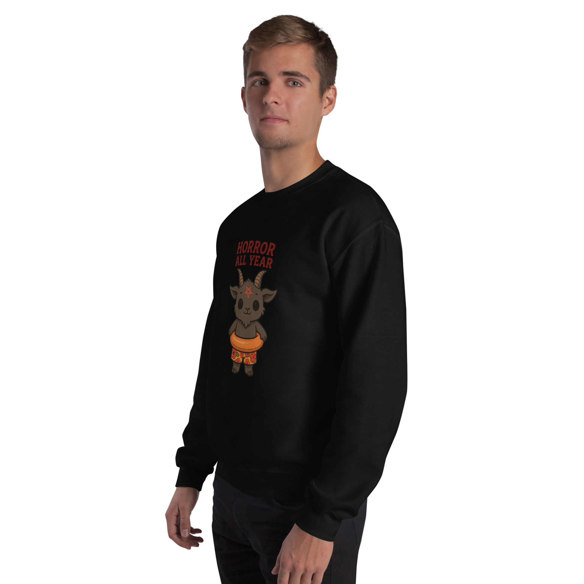 This is a man with blonde hair wearing a black sweatshirt with a cartoon illustration of a baby Baphomet goat with curved horns and a playful grin, wearing bright floral swim trunks while floating in a colorful inner tube. The character is set against a light background with the bold text “Horror All Year” above in red letters
