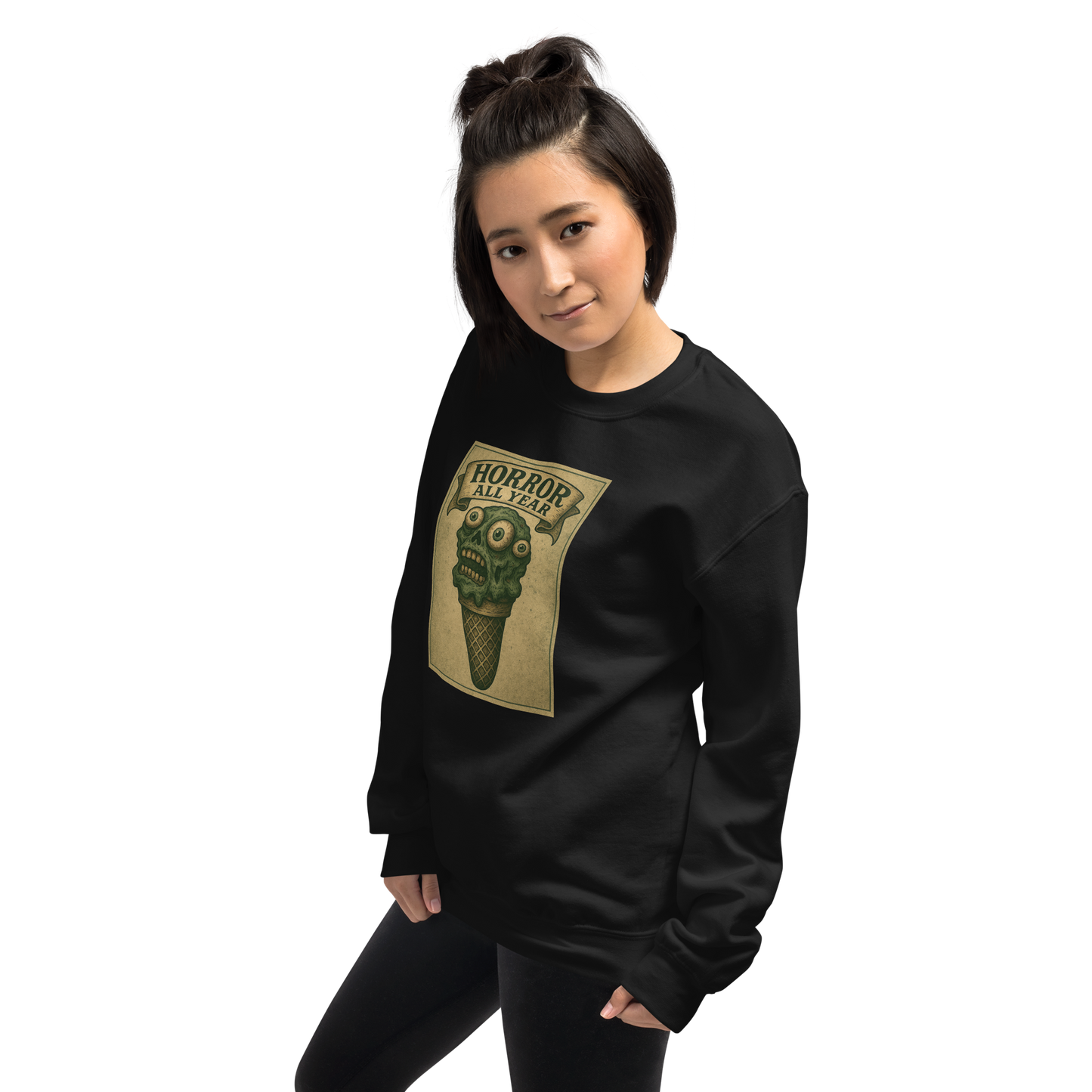 This is a woman with dark hair wearing a black sweatshirt that is a vintage-style illustration of a zombie-themed ice cream cone with a green, melting undead face and bulging eyeballs. Above the cone, a horror banner reads "Horror All Year" on a distressed parchment background